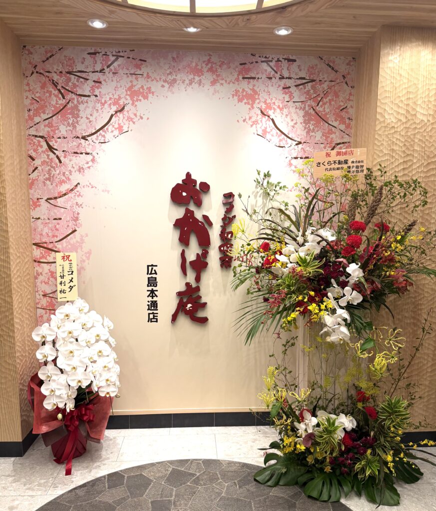 コメダ和喫茶おかげ庵広島本通店の正面看板とオープン祝いのお花
